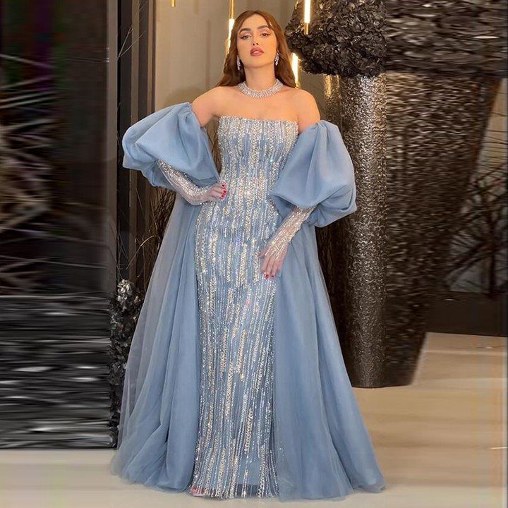 Woman wearing a light blue sequined floor-length gown with voluminous tulle sleeves and skirt.
