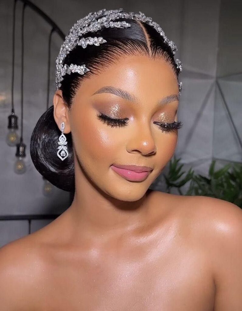 Woman wearing sparkling silver bridal headband and dangling diamond earrings with glamorous makeup.