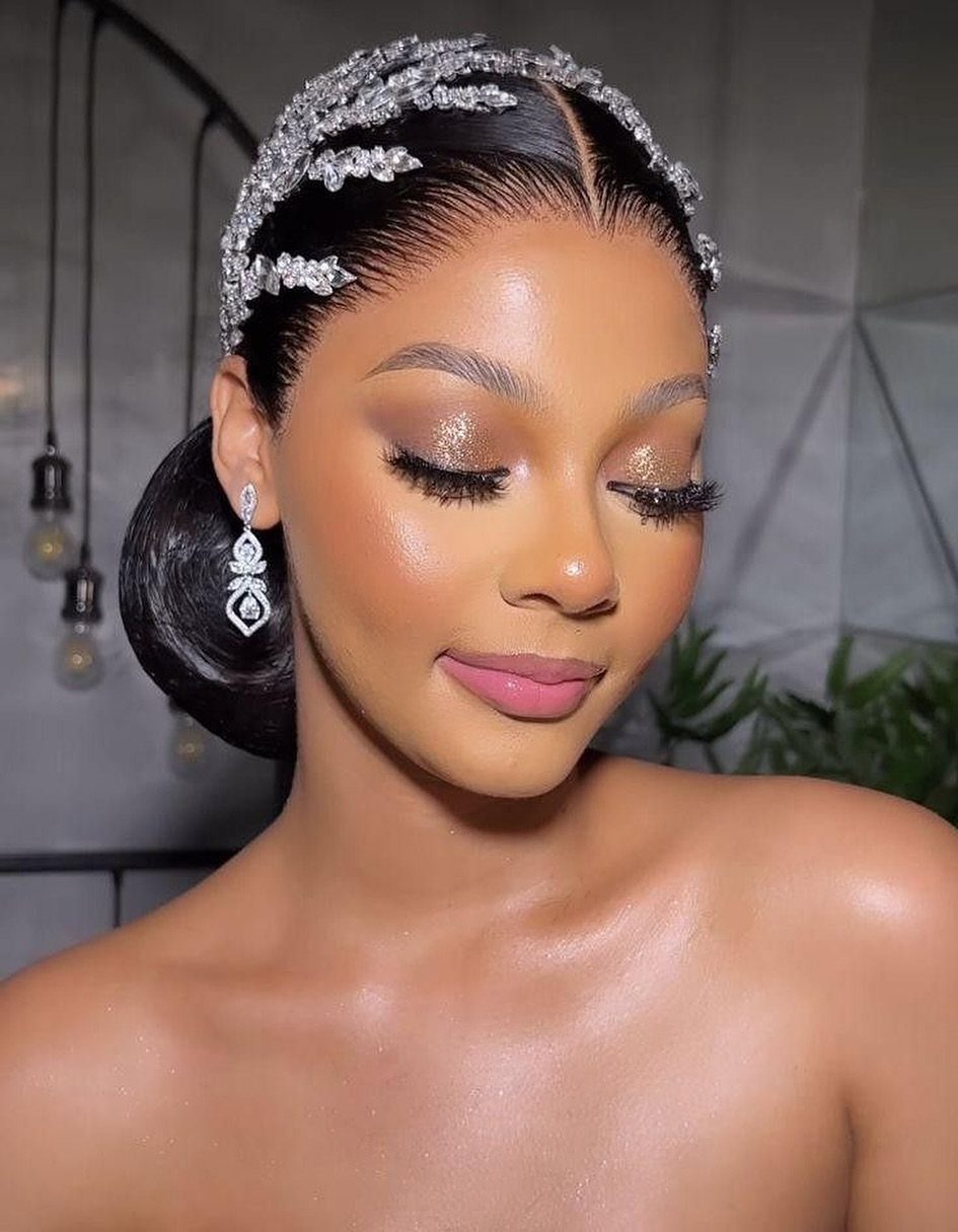 Woman wearing sparkling silver bridal headband and dangling diamond earrings with glamorous makeup.